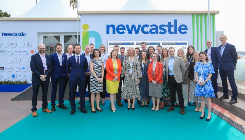 Team standing next to Invest Newcastle sign