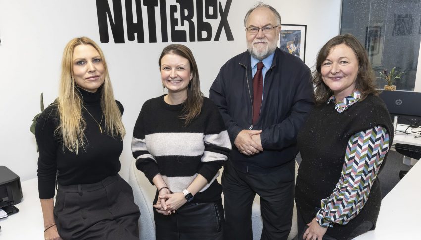 Ali, Jen, Cllr Brain and Lisa all stood in front of Natterbox sign in office smiling towards camera.