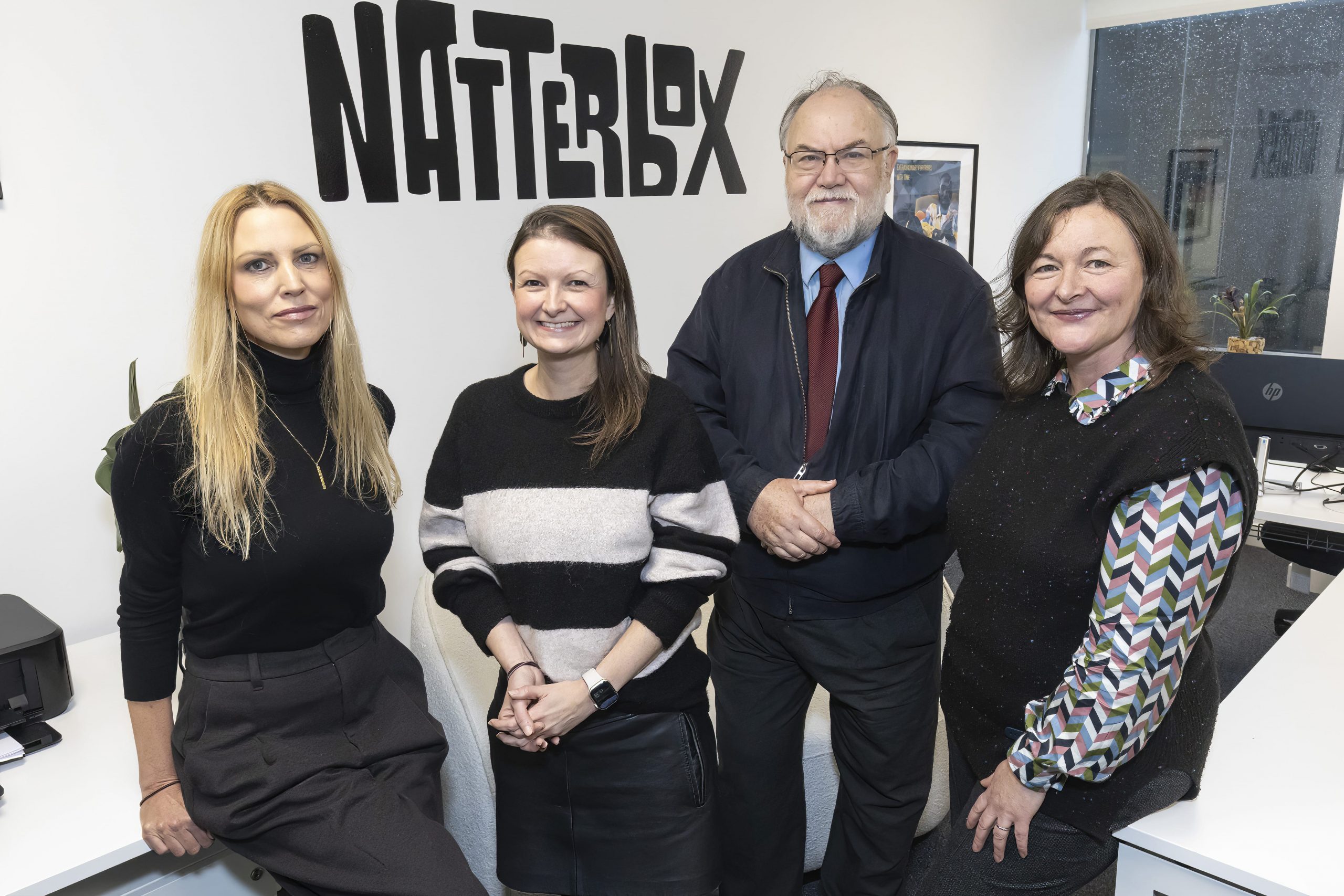 Ali, Jen, Cllr Brain and Lisa all stood in front of Natterbox sign in office smiling towards camera.