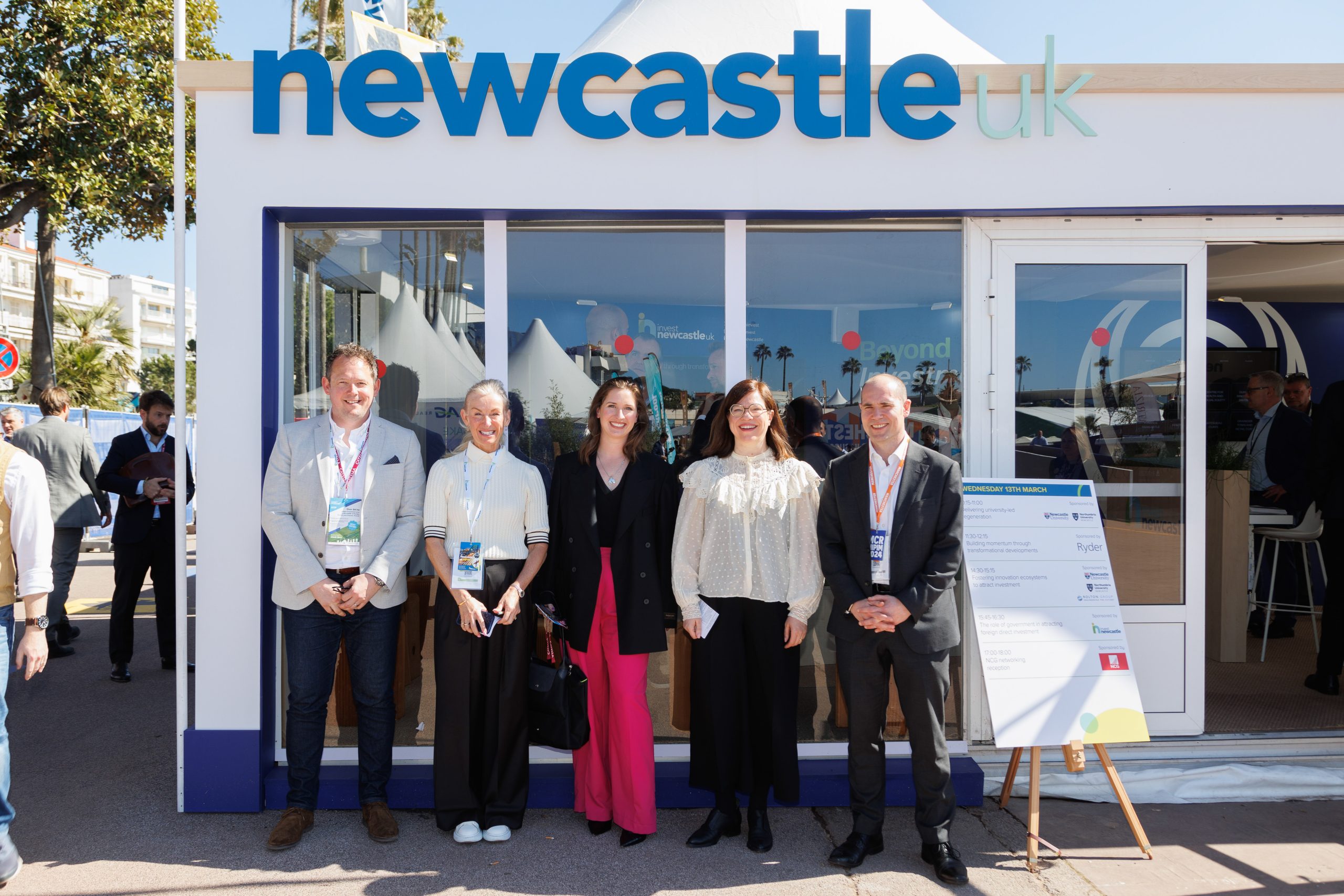 Four people stood in front of Newcastle pavilion smiling to camera