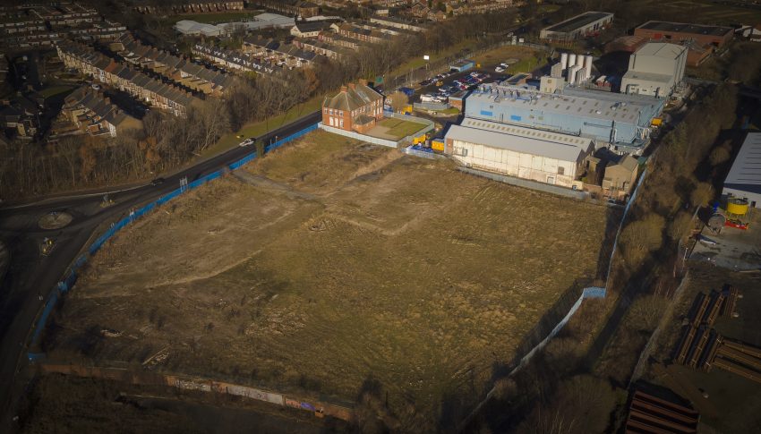Aerial shot of the Neptune Park site, there is a large patch of grass with warehouse to the top right of the image.