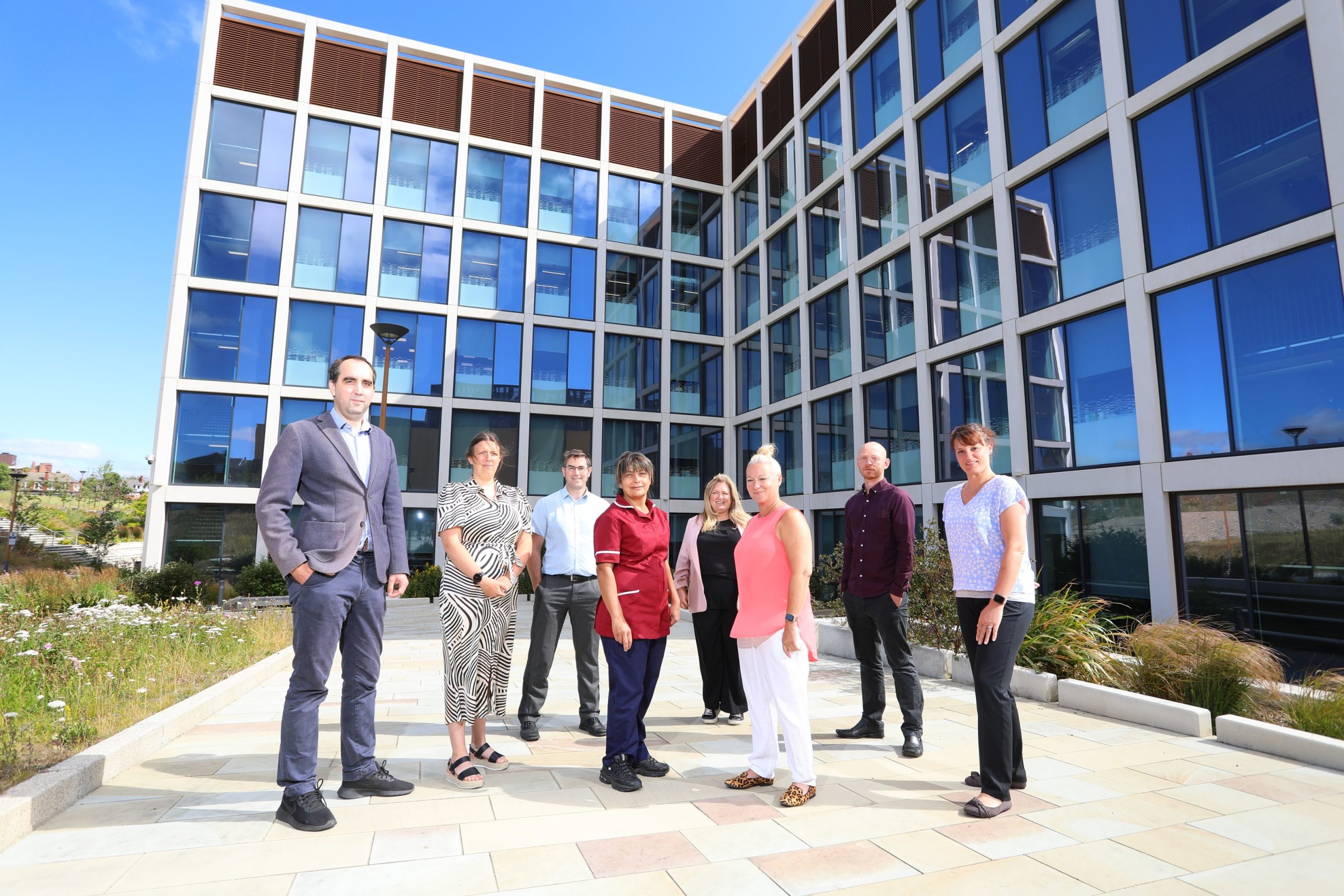 The lab team stood outside The Biosphere building in bright sunshine.