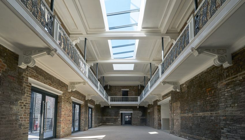 Interior of restored building. The walls are exposed brick and the ceiling has bright windows.