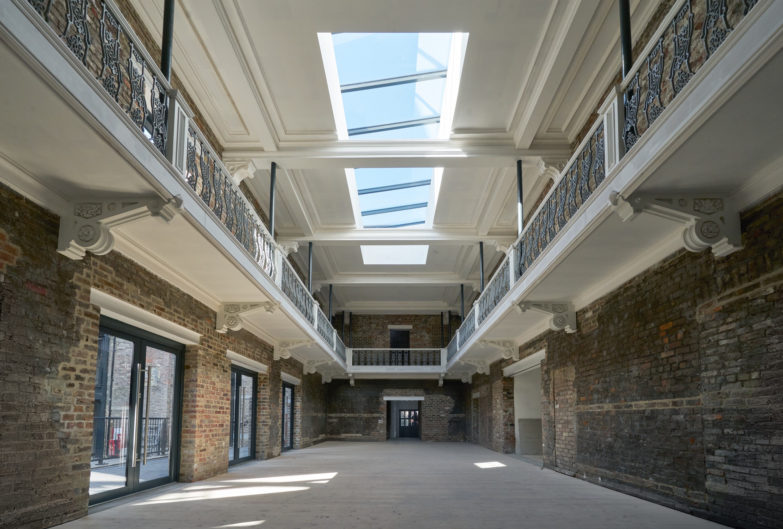 Interior of restored building. The walls are exposed brick and the ceiling has bright windows.