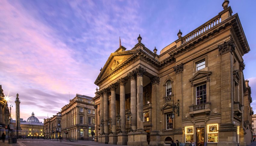 External image of Newcastle's Theatre Royal with pink and purple sunset sky stretching out ahead