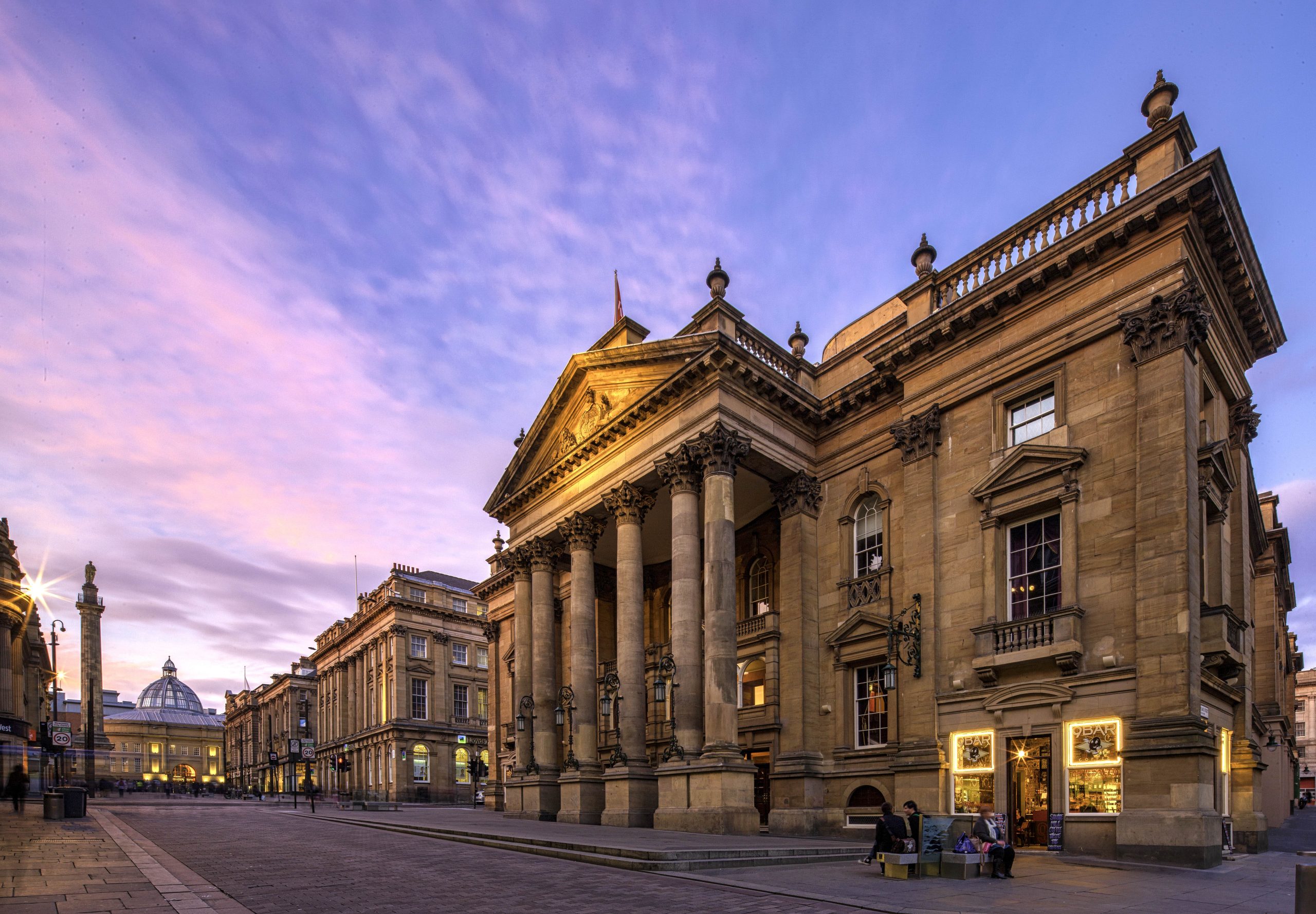 External image of Newcastle's Theatre Royal with pink and purple sunset sky stretching out ahead