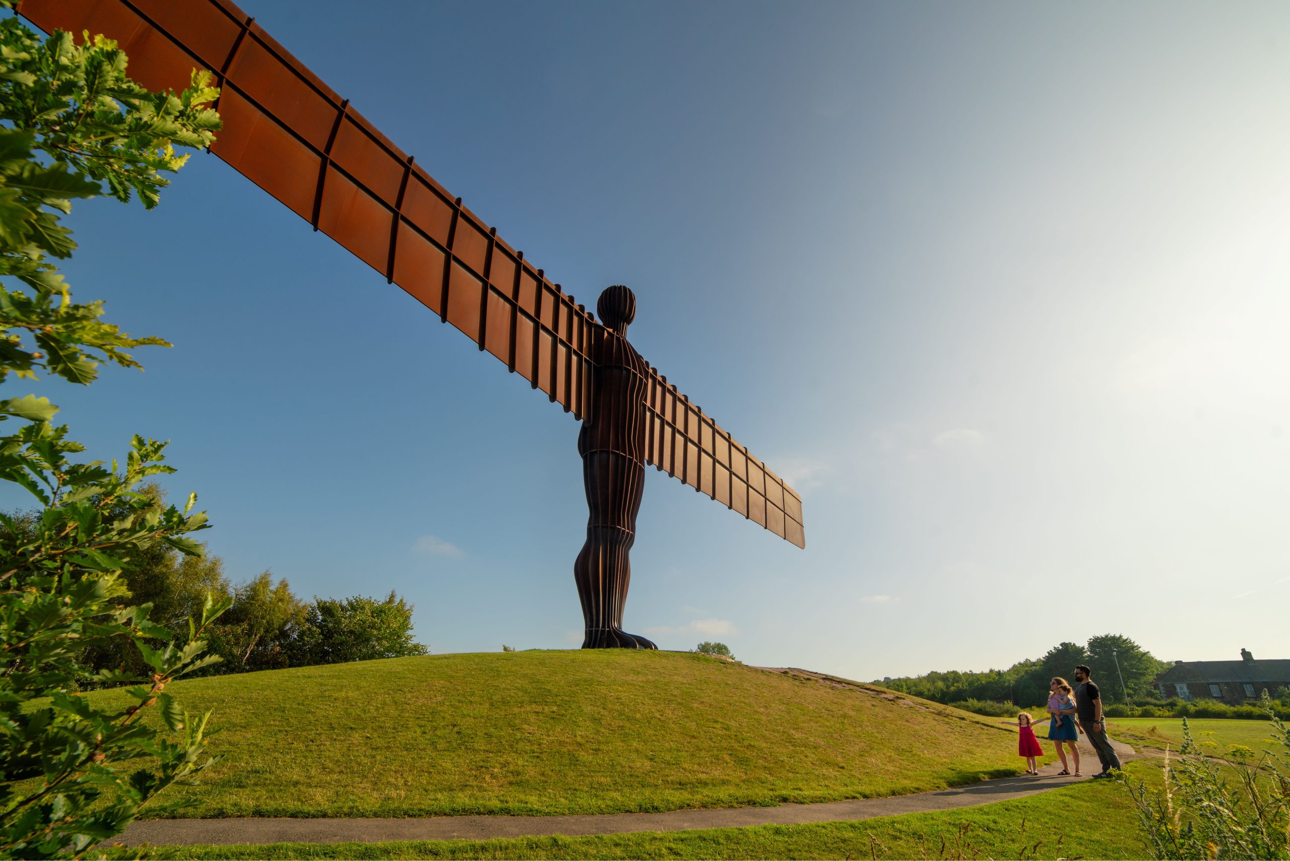 Image of Angel of the North statue on a grassy hill against a blue sky.