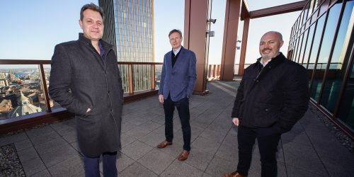 Three people from Broadoak and Tier One Captial on a terrace overlooking the Newcastle skyline.