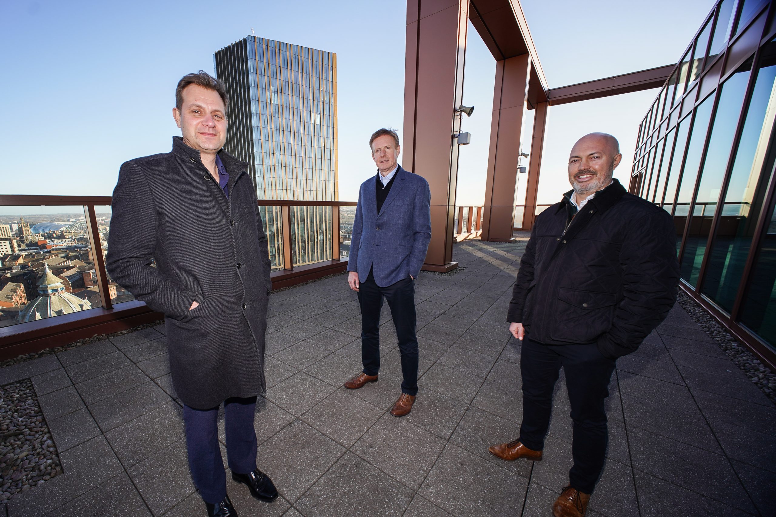 Three people from Broadoak and Tier One Captial on a terrace overlooking the Newcastle skyline.