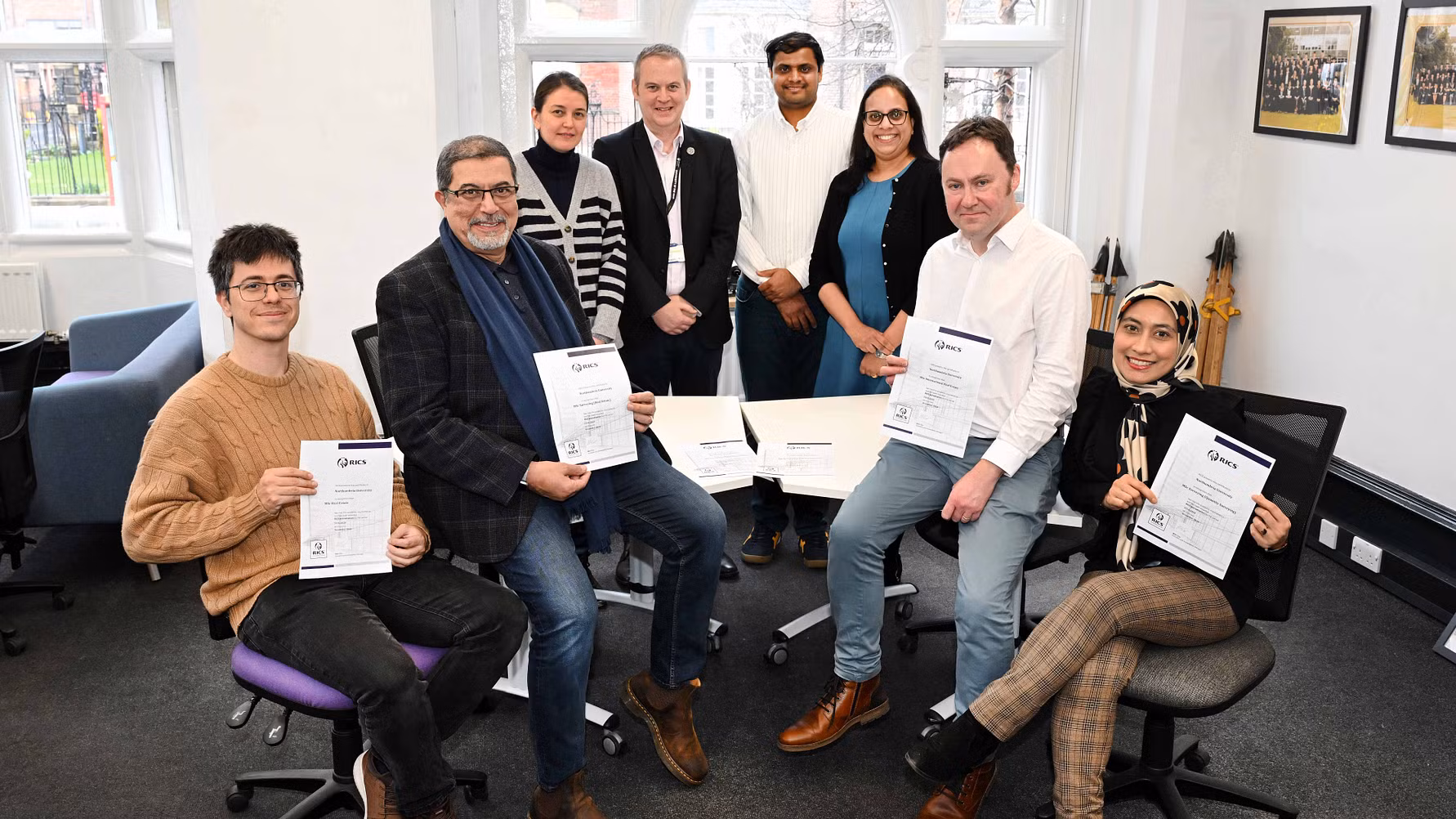 Members of staff from the Department of Architecture and Built Environment at Northumbria University in a room holding up certificates