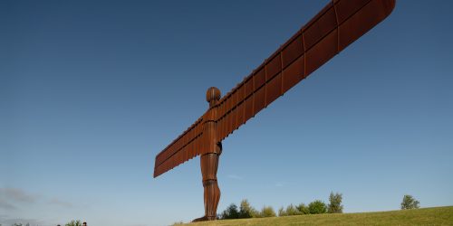 Angel of the North statute on the top of a hill in the sunshine.
