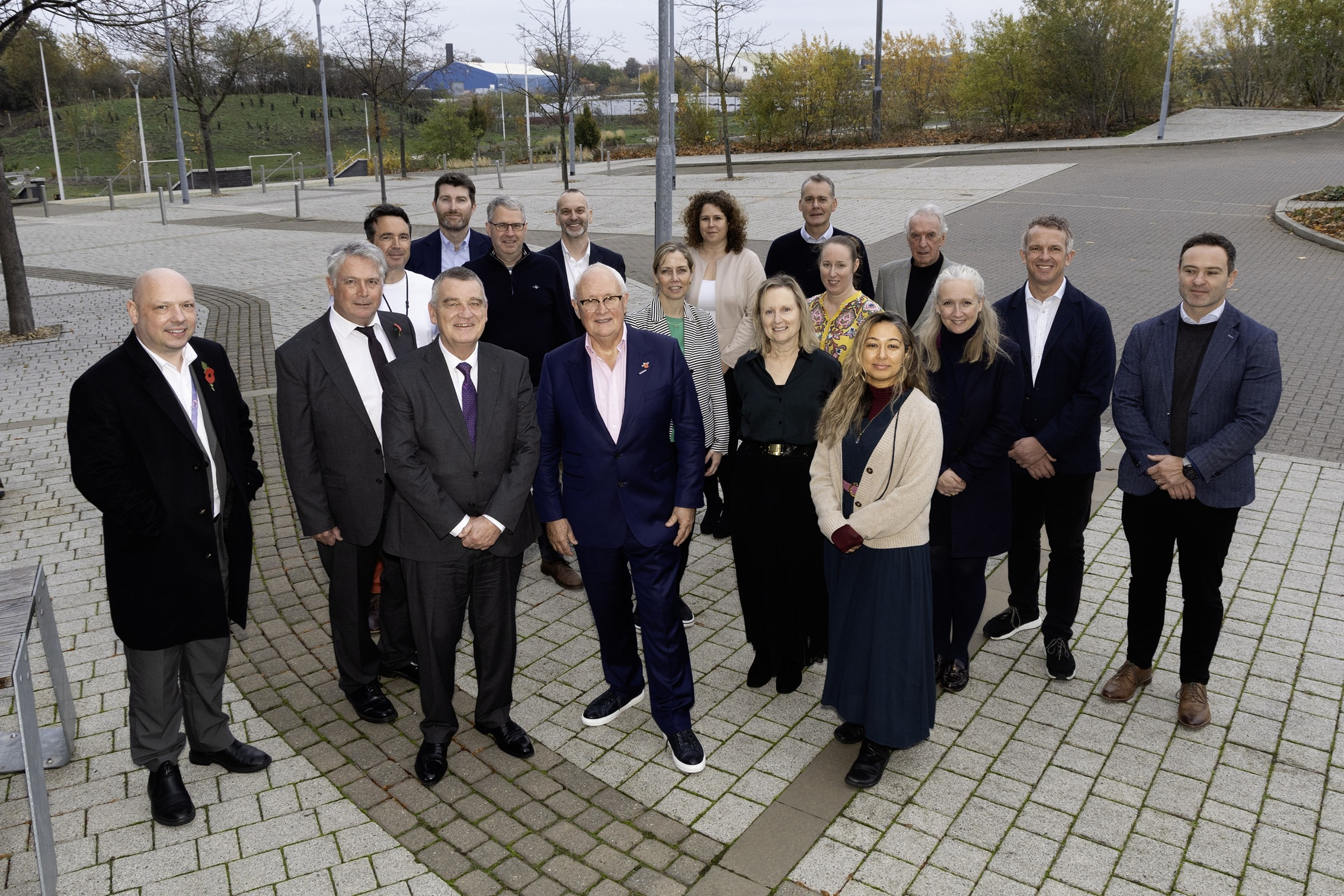 Group of stakeholders in business attire stood in vacant car park.
