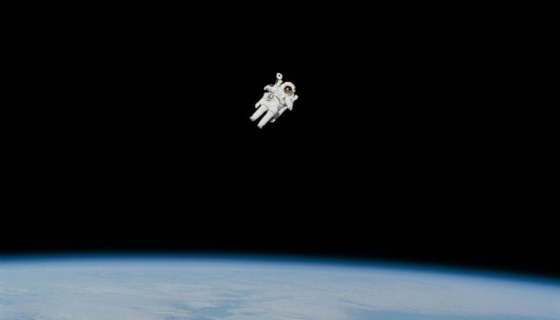 Astronaut floating around above Earth in a white space suit