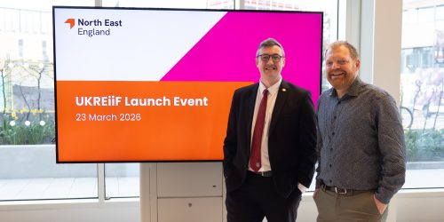 Cllr Mordey and Phil Witcherley standing together in front of the UKREiiF launch event presentation screen.
