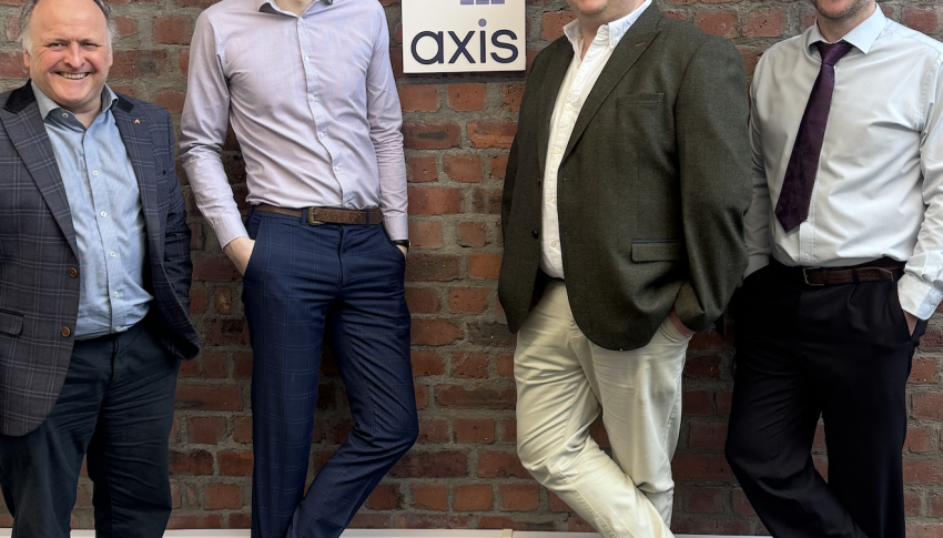 Four Axis Newcastle staff standing against brick wall with Axis branded sign in the middle.