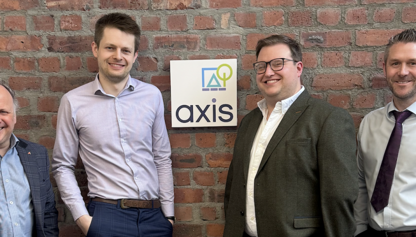 Four Axis Newcastle staff standing against brick wall with Axis branded sign in the middle.